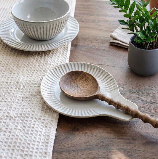 White ceramic spoon rest with a wooden spoon